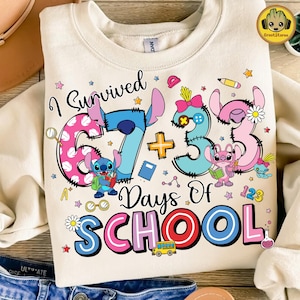 May include: Cream-coloured sweatshirt with a colourful graphic. The design features the text "I Survived 67 + 33 Days Of SCHOOL" and cartoon characters. School-themed illustrations include a bus, stars, and a beaker.
