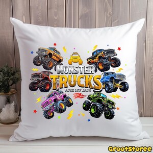 May include: White throw pillow featuring a colorful design of monster trucks. The pillow has a central text that reads "MONSTER TRUCKS ARE MY JAM". The trucks are in various colors, including orange, blue, pink, and green, with star and lightning bolt accents.