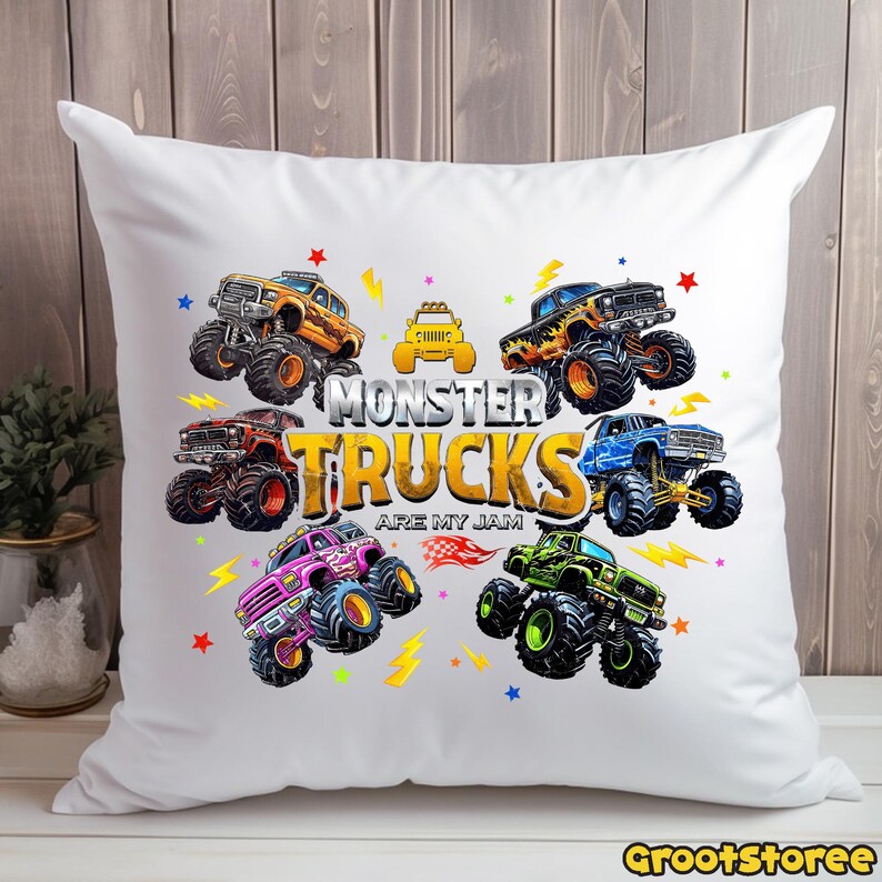 May include: White throw pillow featuring a colorful design of monster trucks. The pillow has a central text that reads "MONSTER TRUCKS ARE MY JAM". The trucks are in various colors, including orange, blue, pink, and green, with star and lightning bolt accents.