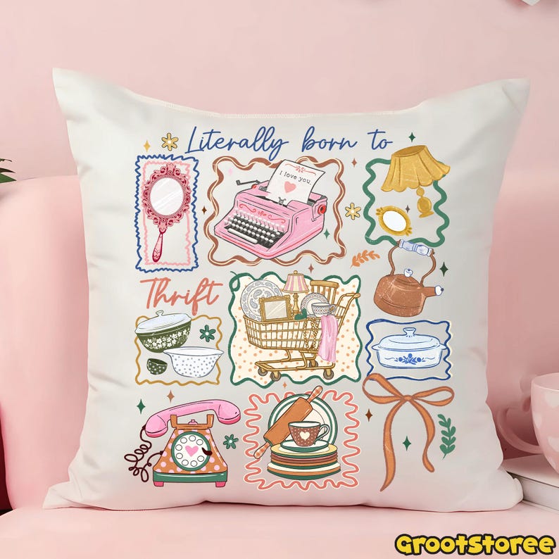 May include: White throw pillow with a colorful graphic design featuring vintage items like a typewriter, mirror, and telephone. The text "Literally born to Thrift" is displayed in blue script. The pillow is on a pink surface.