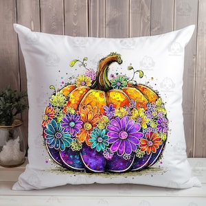 May include: A decorative white pillow featuring a vibrant, watercolor-style pumpkin design. The pumpkin is a mix of orange, yellow, and purple, adorned with colorful flowers in shades of blue, purple, orange, and yellow. The pillow is a square shape.