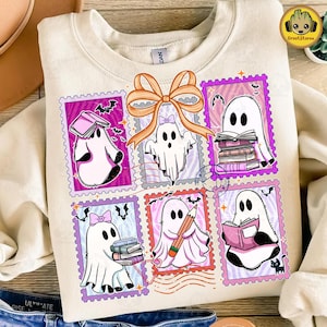 May include: Cream-colored sweatshirt featuring a colorful graphic of ghost characters in postage stamp frames. The ghosts are depicted with books, pencils, and bows. Bats and a black cat are also included in the design.