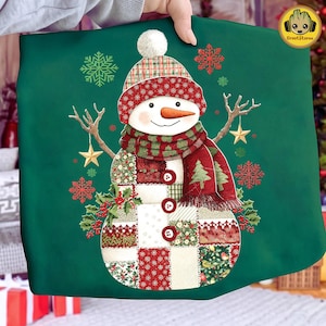 Pode incluir: Uma almofada de Natal verde com um design de boneco de neve em patchwork. O boneco de neve tem um nariz de cenoura, um cachecol vermelho e verde e um chapéu xadrez com um pompom branco. O design inclui flocos de neve, azevinho e estrelas.