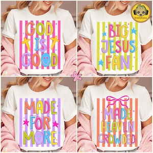 May include: Four white t-shirts with colorful text designs. The designs include "GOD IS GOOD", "BIG JESUS FAN", "MADE FOR MORE", and "MADE HEAVEN CROWDED". Each shirt has a different striped background.