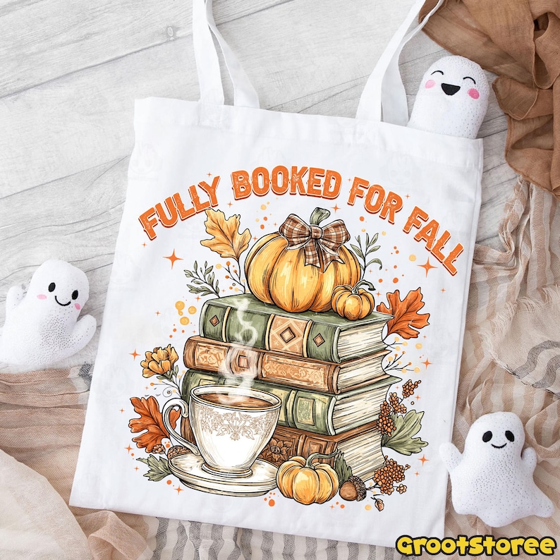 May include: White tote bag printed with "FULLY BOOKED FOR FALL" in orange. The design includes a stack of books, a pumpkin with a plaid bow, a cup of coffee, and autumn leaves. Two small ghost plushies are visible.