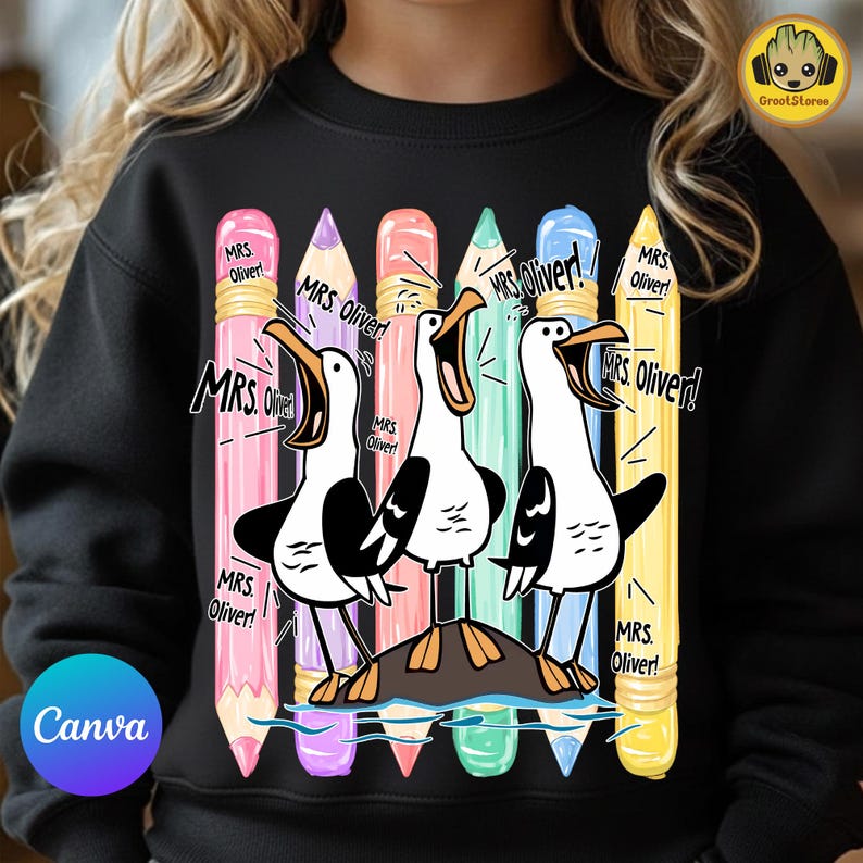 May include: A black sweatshirt featuring a graphic of three white seagulls with black wings standing on a rock, surrounded by five colorful pencils in pink, purple, peach, teal, and yellow. The text "MRS. Oliver!" is repeated multiple times.