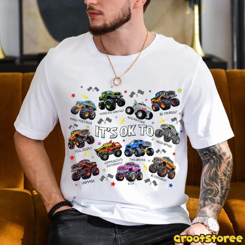 K&ouml;nnte beinhalten: Wei&szlig;es T-Shirt mit bunten Monstertruck-Grafiken und S&auml;tzen wie "Make Mistakes" und "It's OK To". Das Shirt hat einen Rundhalsausschnitt und kurze &Auml;rmel. Der Text "Grootstoree" befindet sich unten rechts.