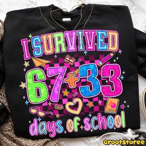May include: Black sweatshirt with the text "I Survived 67 + 33 days of school" in colorful, outlined letters. The design includes a checkered background, stars, and school-themed graphics like a pencil and paper airplane.
