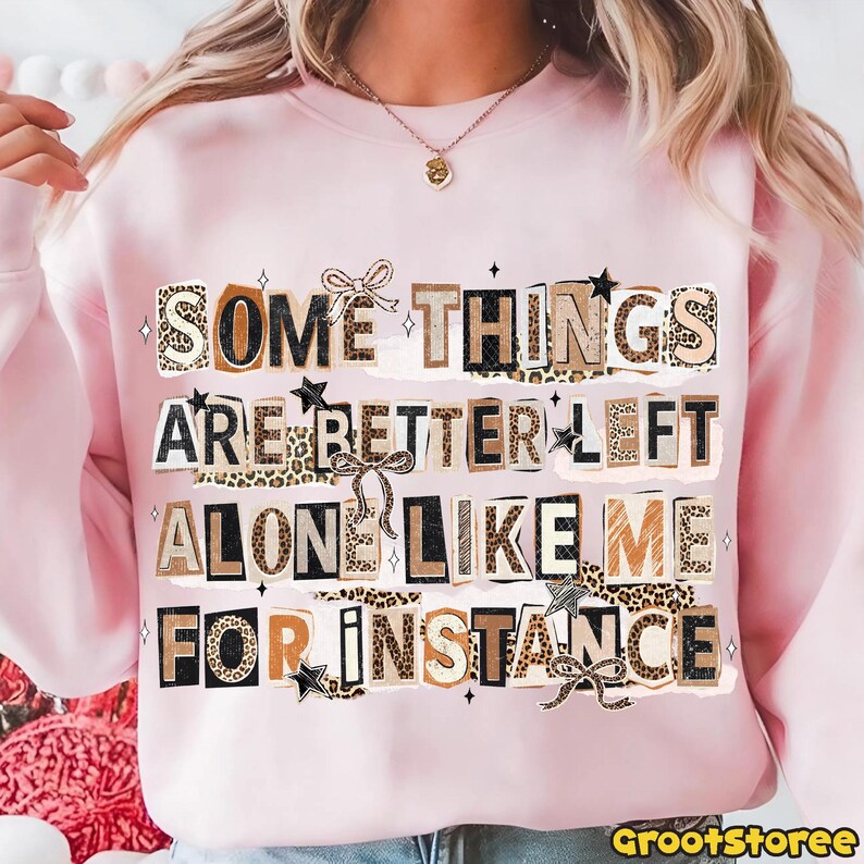 Puede incluir: Sudadera rosa claro con el texto "SOME THINGS ARE BETTER LEFT ALONE LIKE ME FOR INSTANCE" en un estilo collage. El texto incorpora estampado de leopardo, lazos y estrellas.