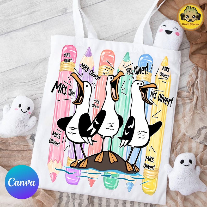 May include: A white tote bag featuring a graphic of three seagulls standing on a rock, surrounded by colorful pencils. The text "MRS. Oliver!" is repeated multiple times around the birds. The design includes pink, purple, orange, green, blue, and yellow pencils.