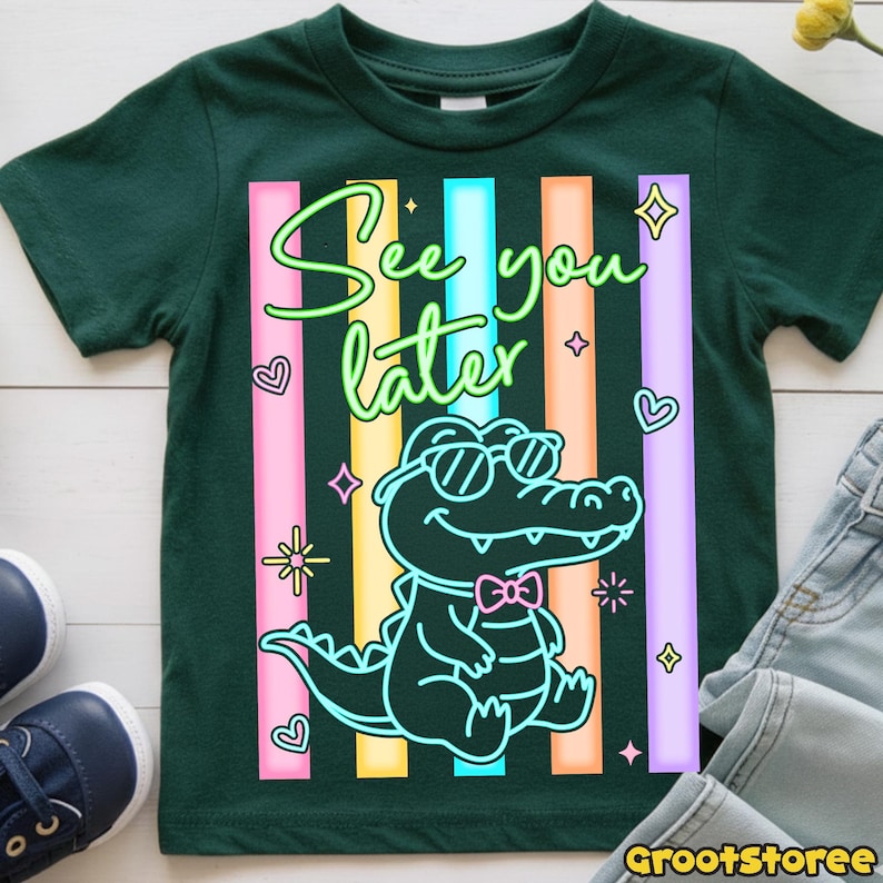May include: Dark green t-shirt featuring a cartoon alligator wearing sunglasses and a bow tie, with the text "See you later." The design includes colorful vertical stripes and decorative elements. A fun and playful design for kids.