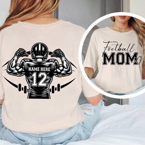 May include: Beige t-shirt with a football player graphic on the back, featuring a helmet, the text "NAME HERE", and the number 12. The front of the shirt has the text "Football MOM".