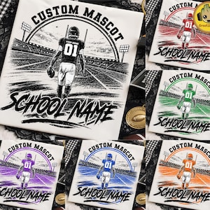 Puede incluir: Una camiseta blanca con un gráfico de un jugador de fútbol americano en un campo con el texto CUSTOM MASCOT y SCHOOL NAME. El diseño está disponible en varias variaciones de color, incluyendo acentos en rojo, verde, morado, azul y naranja.