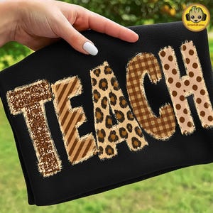 May include: A black fabric item featuring the word TEACH in large, bold letters. Each letter has a distinct pattern: the T is brown glitter, the E has brown diagonal stripes, the A is leopard print, the C is brown plaid, and the H has brown polka dots.