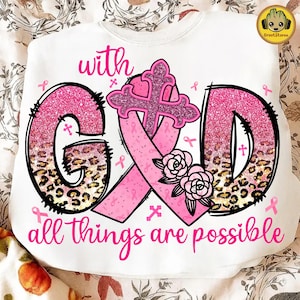 以下が含まれることがあります： ピンク色の「with GOD all things are possible」という文字が書かれた白いスウェットシャツ。「G」と「D」の文字は黒い縁取りで、ピンクのグリッターとヒョウ柄で埋められています。中央にはピンクのリボンと十字架があります。