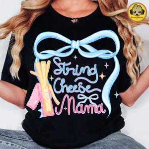 May include: Black t-shirt with a colorful graphic design. The design features the words "String Cheese Mama" in a whimsical font, surrounded by a light blue bow and cheese illustrations. The shirt is a casual wear item.