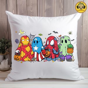 May include: A white throw pillow featuring a graphic illustration of four characters dressed as ghosts for Halloween. The characters resemble Iron Man, Captain America, Spider-Man, and a green monster, each holding a small orange pumpkin bucket.