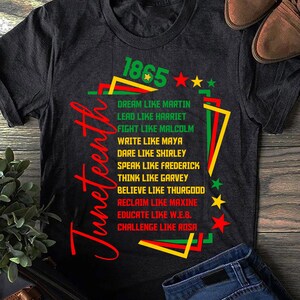 May include: Dark gray t-shirt with the word "Juneteenth" in red script. The shirt features text in green, red, and yellow, including "1865" and phrases like "Dream like Martin" and "Lead like Harriet."