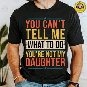 Puede incluir: Camiseta negra con un gráfico de estilo vintage que dice "You can't tell me what to do you're not my daughter".
