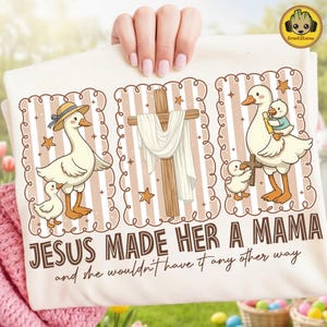 May include: Cream-coloured t-shirt with three illustrated panels. The panels show geese with ducklings, a cross, and the text "JESUS MADE HER A MAMA and she wouldn't have it any other way". The geese are wearing hats and carrying crosses.