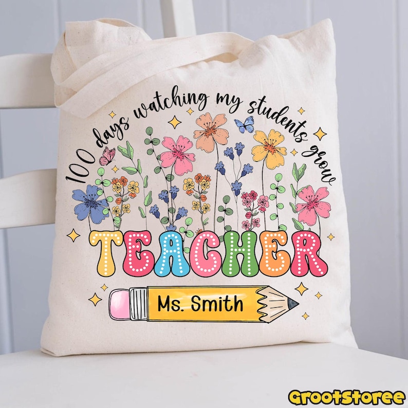 May include: Cream-colored tote bag with a colorful floral design and the words "100 days watching my students grow TEACHER Ms. Smith" printed on it. A pencil graphic is also included.