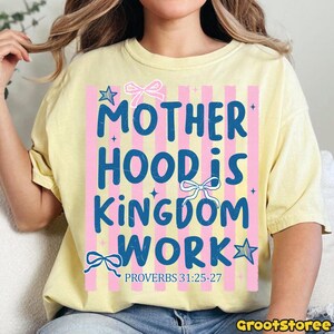 Pu&ograve; includere: T-shirt giallo chiaro con la scritta blu "MOTHERHOOD IS KINGDOM WORK", accentuata da strisce rosa, fiocchi e stelle. &Egrave; incluso anche il testo "PROVERBI 31:25-27". La maglietta ha uno scollo tondo.