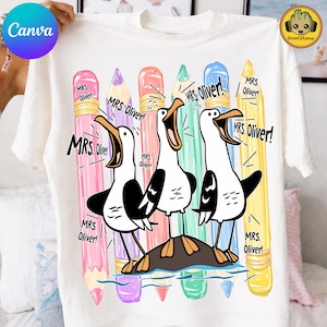 May include: A white t-shirt featuring a graphic of three seagulls standing on a rock, surrounded by five colorful pencils in pink, purple, coral, teal, and yellow. The text "MRS. OLIVER!" is printed multiple times around the birds and pencils.