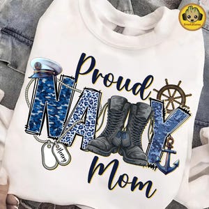 May include: White sweatshirt with the words "Proud Navy Mom" in navy blue script. The word "NAVY" is designed with a camouflage pattern, leopard print, and military-themed graphics, including boots, a ship's wheel, and an anchor.