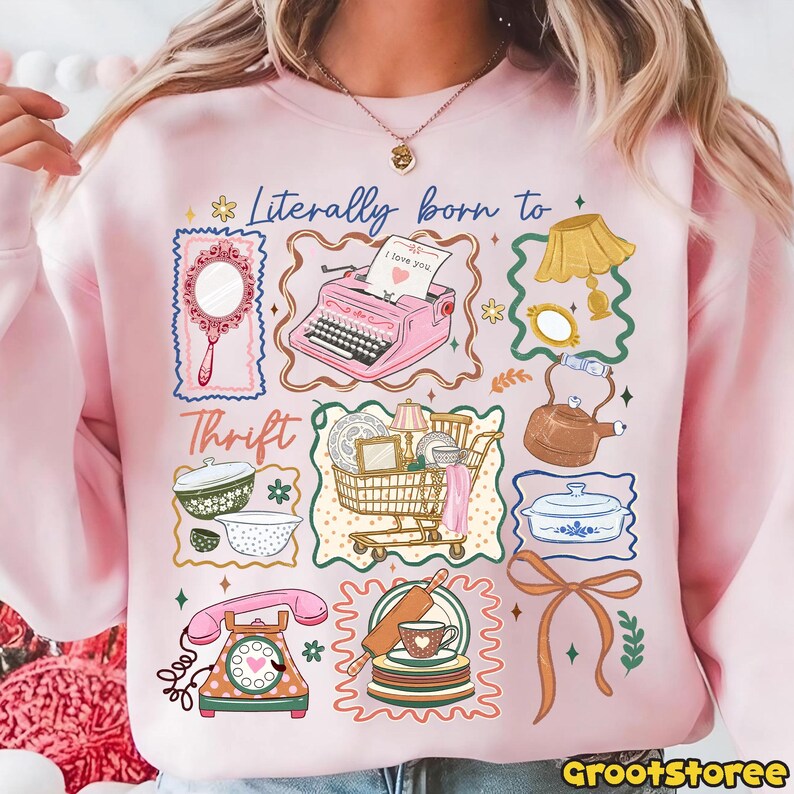 May include: Pink sweatshirt with a colorful graphic design featuring vintage items like a typewriter, mirror, and shopping cart. The text "Literally born to Thrift" is displayed above the images.