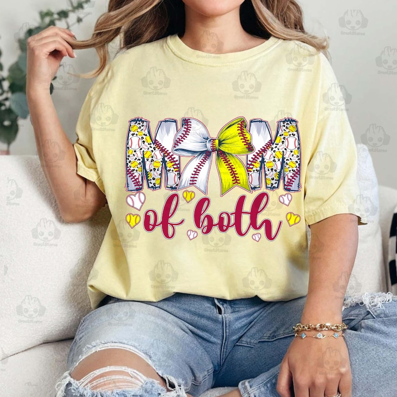 May include: A yellow t-shirt with a graphic of a softball with a bow and the text "Mom of both".