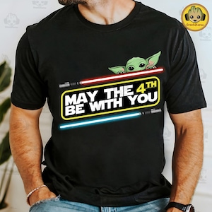 May include: Black t-shirt featuring a green alien character peeking over the top of the text "May the 4th Be With You" with two lightsabers on either side of the text.