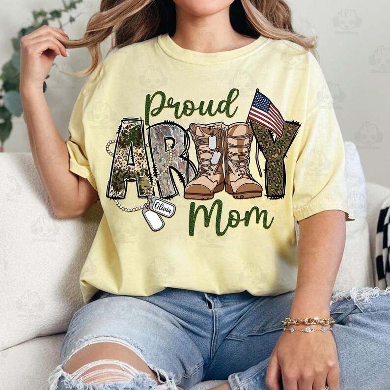 May include: A yellow t-shirt with the words "Proud Army Mom" in green and black lettering. The letters are decorated with camouflage print and a pair of brown military boots. A small American flag is on the right side of the shirt. A silver dog tag with the name "Olivia" is hanging from a chain.