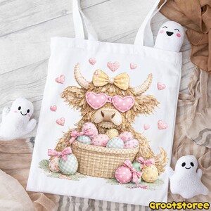 Puede incluir: Bolso tote blanco con una ilustraci&oacute;n de una vaca de las Tierras Altas con gafas de sol en forma de coraz&oacute;n y un lazo. La vaca sostiene una cesta de huevos de Pascua. Corazones y lazos rosas decoran el dise&ntilde;o. El bolso tiene asas blancas.