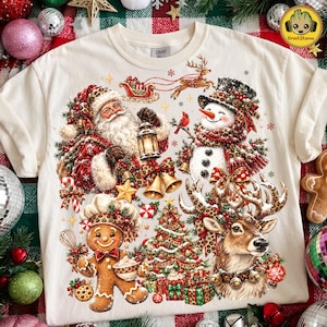 Può includere: Una t-shirt color crema con una grafica natalizia festosa che raffigura Babbo Natale con una lanterna, un pupazzo di neve, un omino di pan di zenzero con cappello da chef e una renna, il tutto decorato con motivi leopardati e addobbi.
