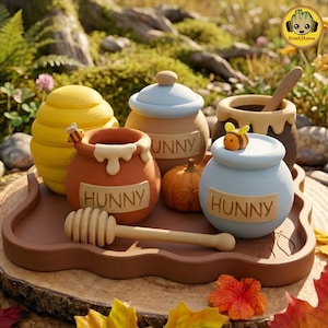 May include: A set of decorative ceramic honey pots on a brown tray, including a yellow beehive-shaped pot, a terracotta pot with a bee, a light blue pot with a bee, and a brown pot with a wooden dipper. Each pot features the text HUNNY.