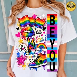 May include: A white t-shirt featuring a colorful graphic print with a rainbow flag, lips, a peace sign, a high-top sneaker, and a rainbow-striped vertical bar with the text BEYOU. Additional text includes love is love and EQUALITY FOR ALL.