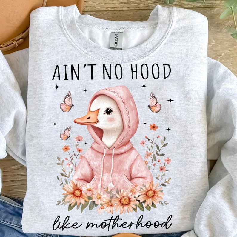 May include: A gray sweatshirt with a white duck wearing a pink hoodie and the text "Ain't no hood like motherhood" with flowers and butterflies.