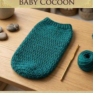May include: A teal crochet baby cocoon with a ribbed top edge, accompanied by a gold-colored crochet hook and a matching ball of yarn. The text reads: CROCHET BABY COCOON, INSTANT DOWNLOAD, HIGH QUALITY DIGITAL PATTERN.
