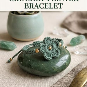 May include: A sage green crochet flower bracelet featuring a central five-petaled crocheted flower, small metallic gold beads, and an adjustable cord closure. The text CROCHET FLOWER BRACELET is displayed in dark green letters at the top of the image.