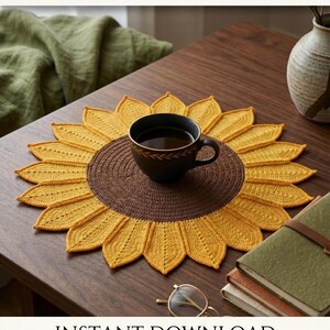 May include: A round crochet coaster shaped like a sunflower with a dark brown center and yellow petals. The text CROCHET COATSER, INSTANT DOWNLOAD, and HIGH QUALITY are visible. A black mug sits on the coaster, which is placed on a wooden surface.