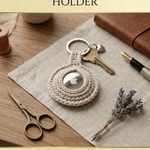 May include: A beige crochet AirTag holder featuring a circular design with a central opening for the device, attached to a silver metal keyring. The text CROCHET AIRTAG HOLDER, INSTANT DOWNLOAD, and HIGH QUALITY is displayed in the image.