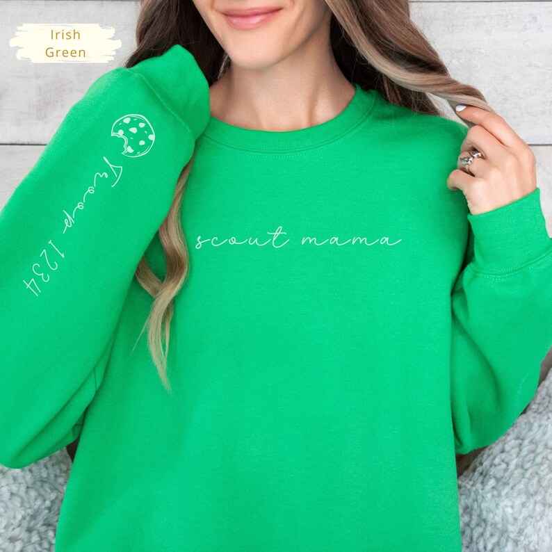 May include: A bright green sweatshirt with the text "scout mama" printed in white on the front. The left sleeve has a white outline of a Girl Scout cookie with the text "#231 Thin Mints" printed vertically.