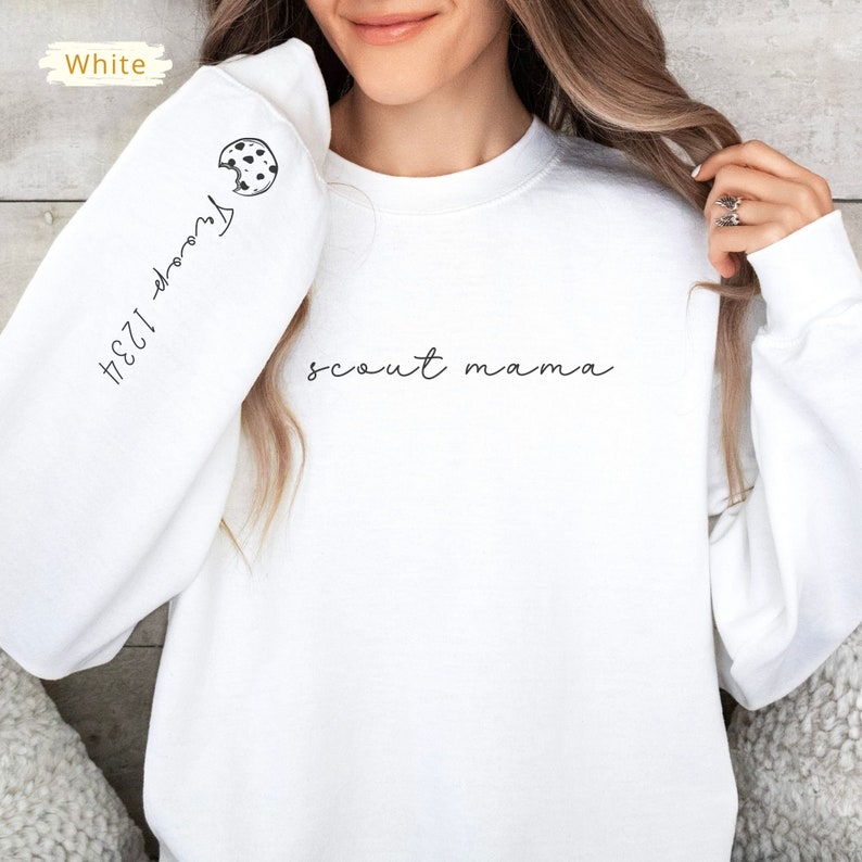 May include: White sweatshirt with the text "scout mama" printed on the front and a cookie graphic with the text "1234-troop" on the sleeve.