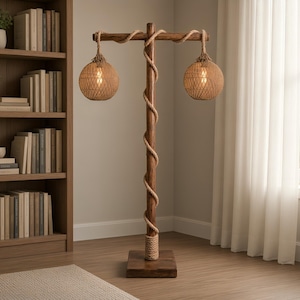Peut inclure: Un lampadaire composé d'un poteau en bois brun foncé avec une base carrée, entouré d'une corde naturelle épaisse. Deux abat-jours sphériques en rotin tressé pendent d'une traverse en bois, chacun contenant une ampoule à lumière chaude.