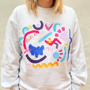 Sweatshirt painted and hand embroidered, with abstract or floral motif.