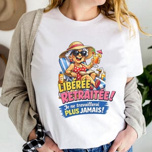 May include: White t-shirt featuring a cartoon illustration of a relaxed elderly person on a beach chair, wearing sunglasses and a hat, holding a drink. The shirt has the text "LIBEREE RETRAITE" and "Je ne travaillerai PLUS JAMAIS!"