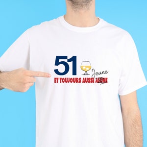 May include: White t-shirt with blue text that says "51" and red text that says "jeune et toujours aussi jeune" with a line through the second "jeune". There is a drawing of a glass of alcohol with ice cubes.