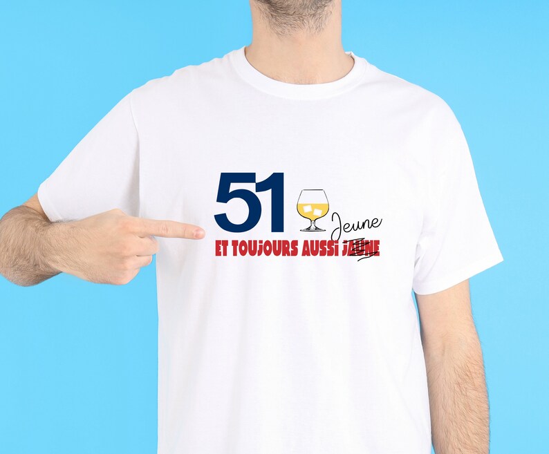 May include: White t-shirt with blue text that says "51" and red text that says "jeune et toujours aussi jeune" with a line through the second "jeune". There is a drawing of a glass of alcohol with ice cubes.