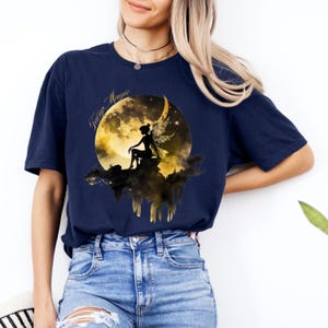 May include: A navy blue t-shirt with a graphic of a fairy sitting on a crescent moon with the text "Fairy Magic".