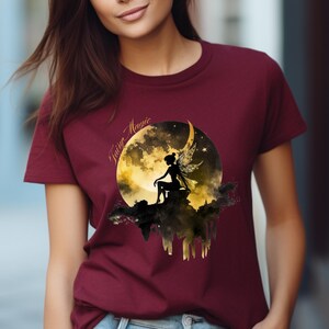 May include: A maroon t-shirt with a graphic of a fairy sitting on a crescent moon with the text "Fairy Magic" above the moon.